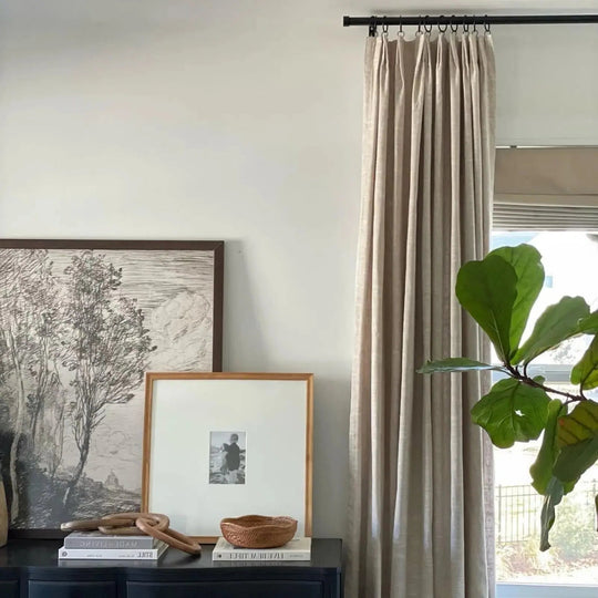 An artfully styled home interior with a dark cabinet displaying a monochromatic landscape print, a framed child&