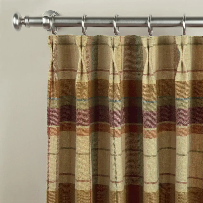 A close-up of a pinch pleat curtain in a rustic plaid pattern featuring beige, brown, plum, and subtle teal lines, suspended from a brushed satin nickel curtain rod with rings and a spherical finial